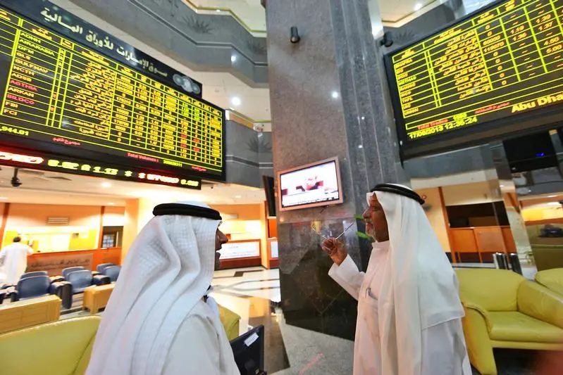 Investors speak as they monitor stocks at the Abu Dhabi Securities Exchange. Image for illustrative purposes , Stringer 