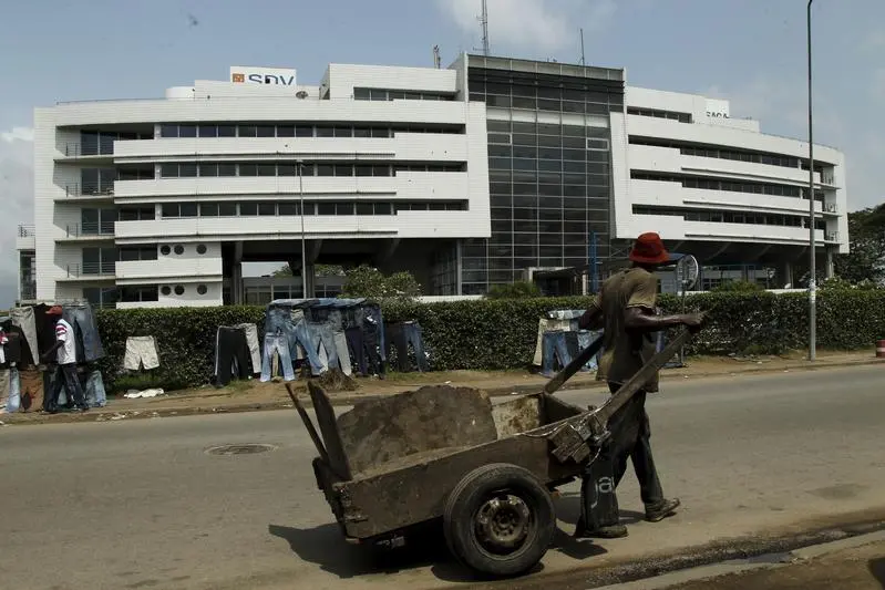 A man carries wood in a cart past the Ivory Coast headquarters of the Bollore group in Abidjan, Ivory Coast, November 12, 2015. A major West African rail scheme being built by French industrial conglomerate Bollore is caught up in a legal action, initiated by a rival firm shortly after the group hired banks to prepare for a Paris bourse listing of the regional project. Picture taken November 12, 2015. REUTERS/Luc Gnago - RTS7NHA , Reuters Images/Luc Gnago - RTS7NHA