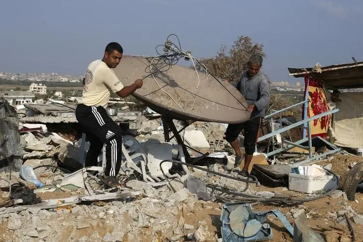 Palestinians salvage a satellite dish from the ruins of their house, which witnesses said was destroyed during the Israeli offensive, on the fourth day of a five-day ceasefire in Johr El-Deek village near the central Gaza Strip August 17, 2014. REUTERS/Ibraheem Abu Mustafa  , Reuters Images/Ibraheem Abu Mustafa 