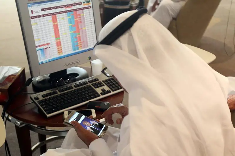A trader uses his smartphone to follow news of U.S. presidential elections as he monitors a screen displaying stock information at Qatar Stock Exchange in Doha, Qatar November 9, 2016. Image for illustrative purposes. , Naseem Zeitoon