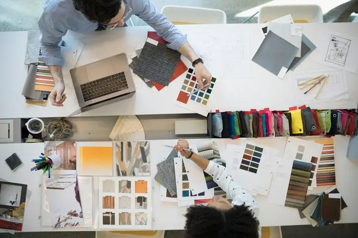Image used for illustrative purpose.\\r\\nOverhead view designers with fabric swatches in conference room meeting. , Getty Images