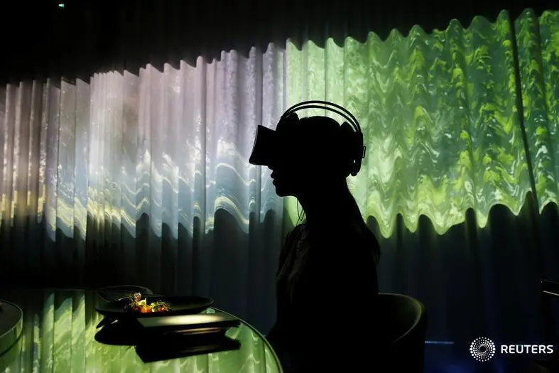 A woman wears VR glasses while the projection mapping is cast on a table and walls during its media preview at \"TREE BY NAKED, yoyogi park\" restaurant in Tokyo, Japan, July 19, 2018. This restaurant incorporates virtual reality, projection mapping, and music to enhance diners\\' enjoyment of their food.   Image used for illustrative purpose. , Reuters Images/Kim Kyung-Hoon  