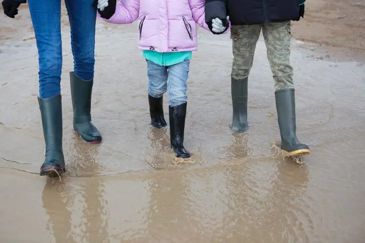 Three children walking through a muddy people , Getty Images/Elva Etienne