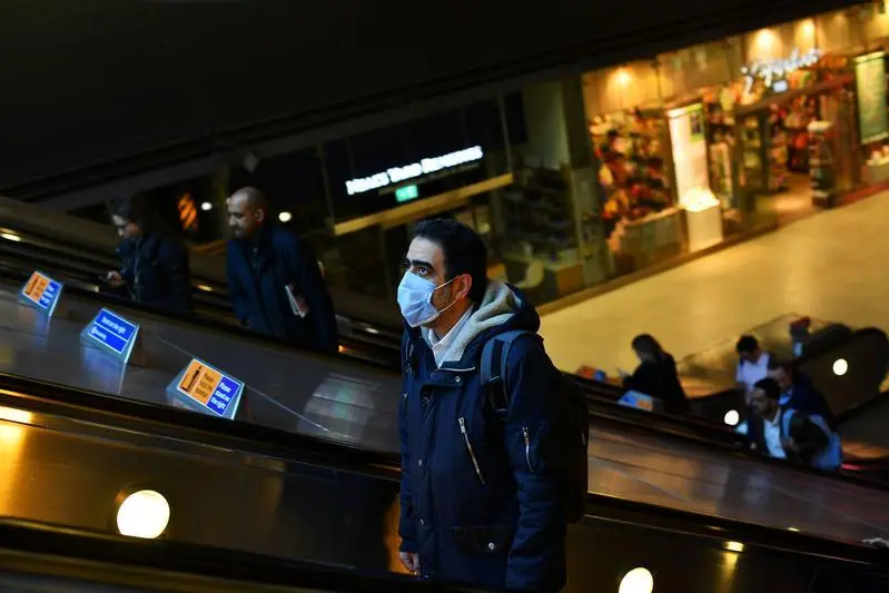 A man wears a mask as commuters walk through Canary Wharf, as the number of coronavirus cases grow around the world, in London, Britain March 16, 2020.  , Reuters Images/Dylan Martinez 