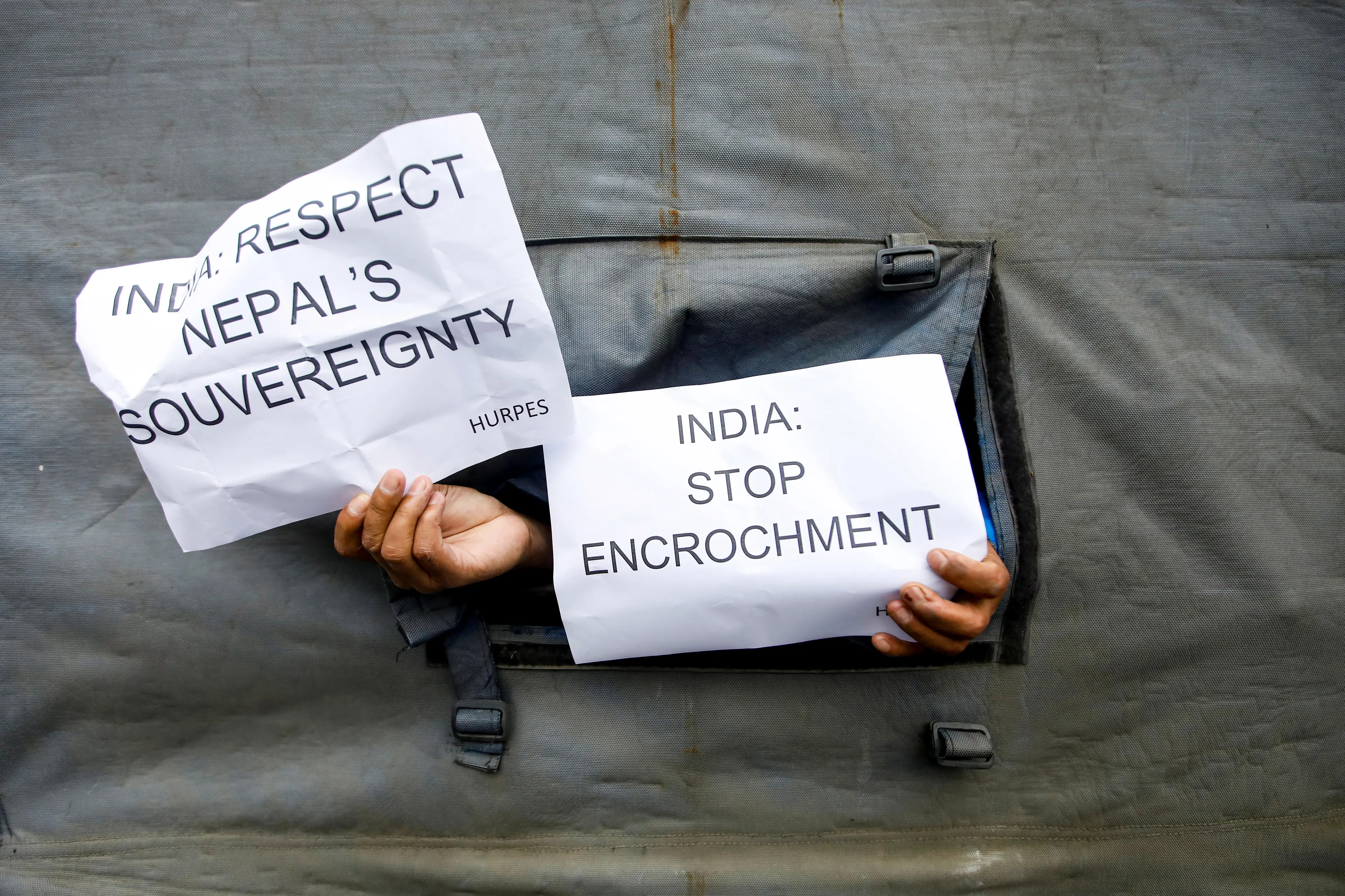 Activist affiliated with \\'Human Rights and Peace Society Nepal\\' displays placards as they get detained while protesting against the alleged encroachment of Nepal border by India in far west of Nepal, during the 50th day of a lockdown imposed by the government amid concerns about the spread of the coronavirus disease (COVID-19), near the Indian Embassy in Kathmandu, Nepal May 12, 2020.  , Reuters Images/Navesh Chitrakar