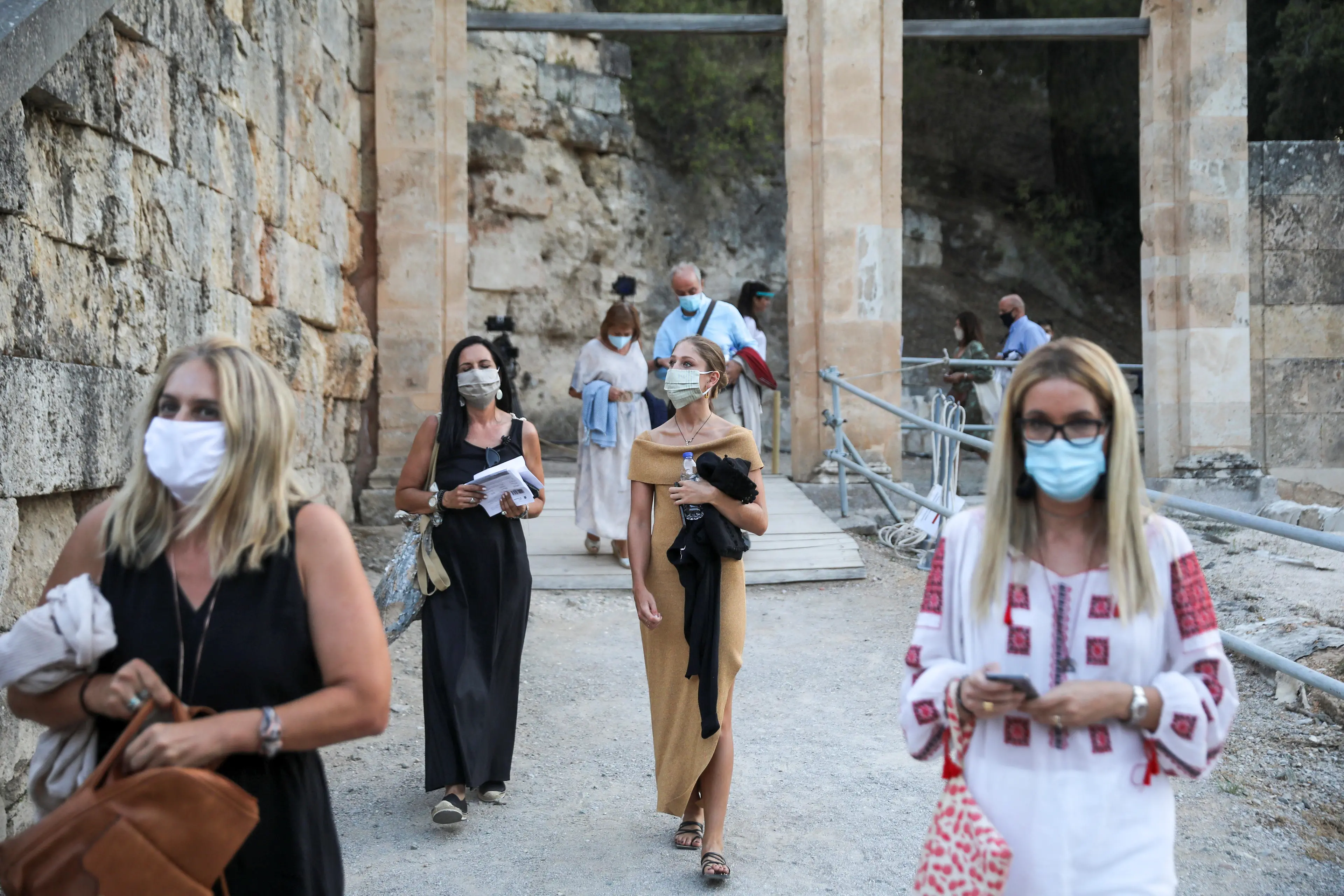 People wearing protective face masks enter the ancient amphitheatre of Epidaurus to watch \"The Persians\", an ancient Greek drama by Aeschylus first performed in 472 BC, following the easing of measures against the spread of the coronavirus disease (COVID-19), in Epidaurus, Greece, July 24, 2020. Picture taken July 24, 2020.  , Reuters Images/Costas Baltas
