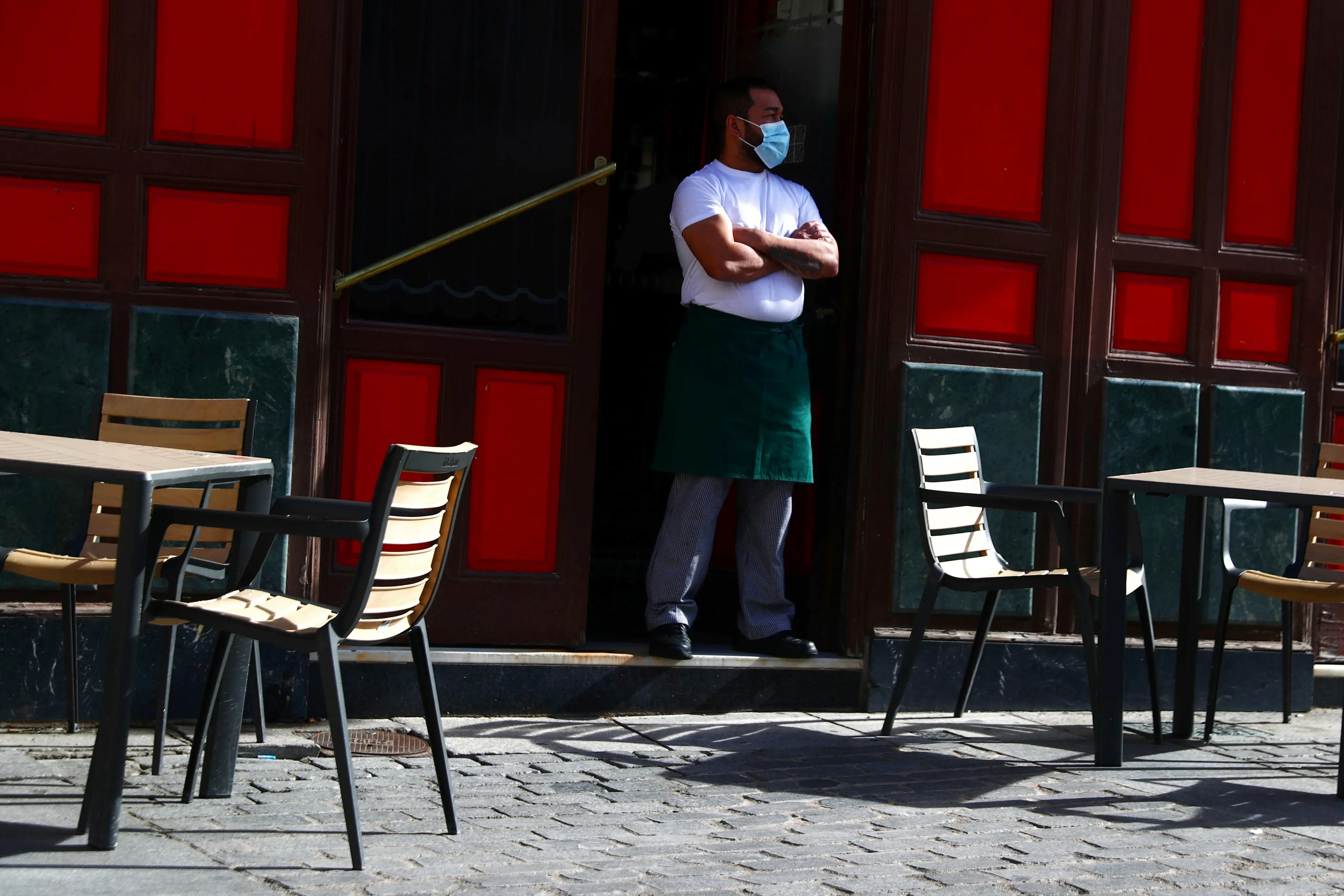 A waiter wearing a protective face mask waits for customers in his terrace amid the outbreak of the coronavirus disease (COVID-19), in Madrid, Spain October 1, 2020. , Reuters Images/Sergio Perez