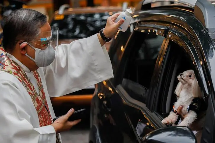 A Catholic priest sprinkles holy water on a dog aboard a vehicle at a drive-thru pet blessing amid the coronavirus disease (COVID-19) outbreak on World Animal Day, in Eastwood Mall, Quezon City, Philippines, October 4, 2020.  , Reuters Images/Eloisa Lopez