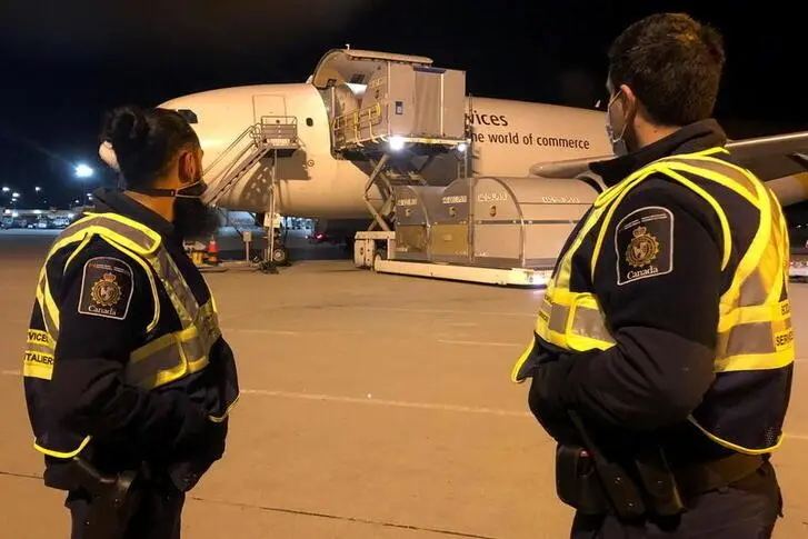 Canada Border Services Agency (CBSA) officers watch as the country\\'s first batch of Pfizer/BioNTEch COVID-19 vaccines arrives at Montreal?Mirabel International Airport in Montreal, Quebec, Canada December 13, 2020. CBSA/Handout via REUTERS.