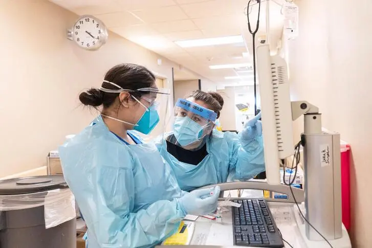 Healthcare workers Leticia Lascano and Stephanie Carden (L) wear personal protective equipments as they discuss about a patient at Medical Arts Hospital in Lamesa, Texas, U.S., December 17, 2020.   , Reuters Images/Go Nakamura