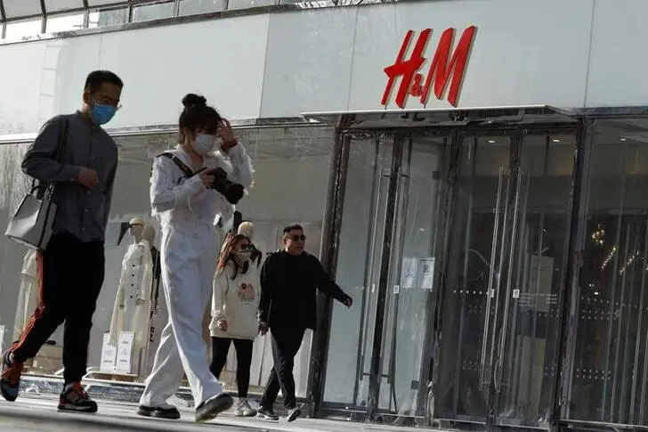 People walk past an H&M store in a shopping area in Beijing, China, March 28, 2021.  , Reuters Images/Thomas Peter