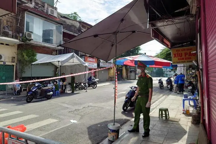 A police officer stands next to a street barricade set up as the country imposes measures to prevent the spread of the coronavirus disease (COVID-19) , amid the COVID-19 pandemic, in Hanoi, Vietnam, August 22, 2021.  , Reuters Images/Staff